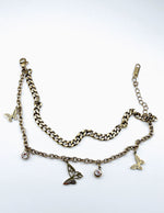 Modeled wrist wearing stacked style non-tarnish gold butterfly charm bracelet for women in UAE.