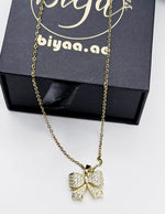 Modern luxury gold and crystal bow statement necklace for women.