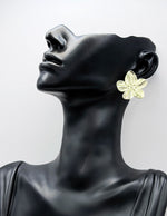 Mannequin head wearing a large floral earring against a white background