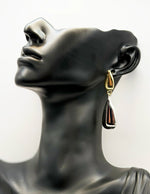 Close up of imitation jewelry uae statement earrings featuring high-shine gold and silver molten texture.