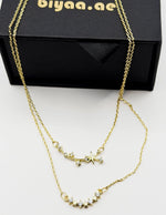 Waterproof and non-tarnish artificial gold double chain necklace resting on silk fabric.