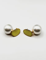Close up of elegant imitation jewelry uae featuring a gold-edged cream stud and oversized faux pearl drop.