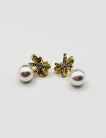 Close up of premium hypoallergenic imitation jewelry featuring a pavé bow and large faux pearl.