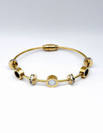Close up of mother of pearl and black enamel style charms on a luxury imitation bracelet.