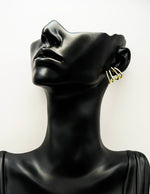 Gold hoop earrings on a black mannequin bust against a white background