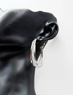 Silver hoop earrings on a black mannequin ear with a white background