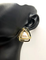 Gold triangle-shaped earring with a pearl center on a black mannequin ear.