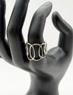 Silver ring on a black mannequin hand against a white background