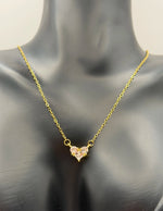 Gold necklace with a heart-shaped pendant on a mannequin.