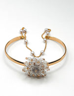 Gold bracelet with a central diamond-like stone on a white background