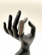Decorative ring on a black mannequin hand against a light background