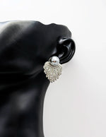 Silver earring with a pearl on a black mannequin ear against a white background