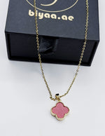 Necklace with a pink clover-shaped pendant in front of a black box with 'biyaa.ae' branding.