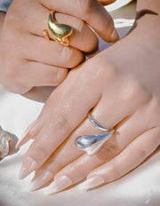 Close-up of hands wearing gold and silver rings on a light background
