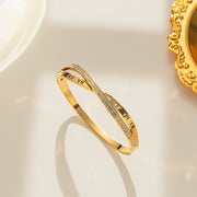 18K gold plated Roman numeral and crystal crossover bangle by Biya Accessoires.