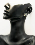 Mannequin head wearing a leaf-shaped earring on a white background