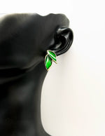 Green leaf-shaped earring on a black mannequin ear against a white background