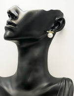 Mannequin head wearing pearl earrings on a white background