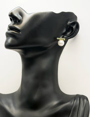 Mannequin head wearing pearl earrings on a white background