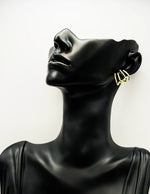Mannequin head wearing gold hoop earrings on a white background