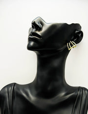 Mannequin head wearing gold hoop earrings on a white background