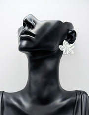 Mannequin head wearing a silver floral earring on a light gray background