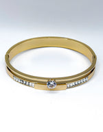 Close up of luxury imitation jewelry featuring a gold cuff with channel-set baguette stones.