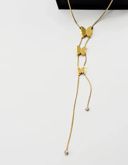 Model adjusting a gold butterfly lariat necklace for a custom fit in Dubai.