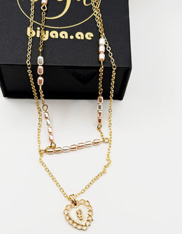 Imitation jewelry featuring a scalloped heart pendant and faux pearls by Biya Accessoires.