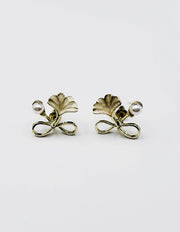 Close up of elegant imitation jewelry uae featuring a golden bow faux pearl and green leaf.