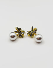 Close up of premium hypoallergenic imitation jewelry featuring a pavé bow and large faux pearl.