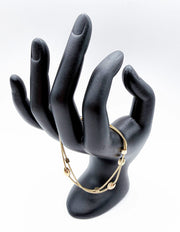 Modeled gold chain bracelet stacked with other jewelry on a woman's wrist.