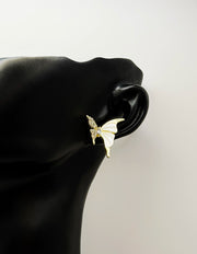 Butterfly-shaped earring on a black mannequin ear against a light gray background