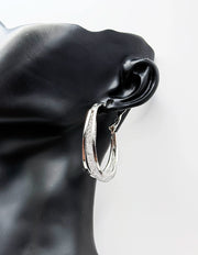 Silver hoop earrings on a black mannequin ear with a white background