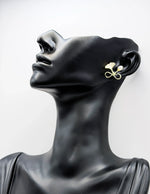 Biya Accessoires gold bow pearl and enamel leaf stud earrings.
