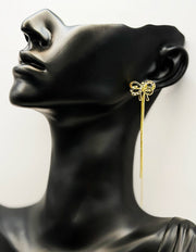 Close up of imitation jewelry uae bow studs featuring gold tassels and pavé crystals.