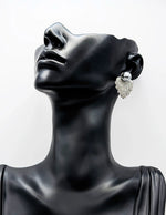 Mannequin head wearing a silver earring on a white background