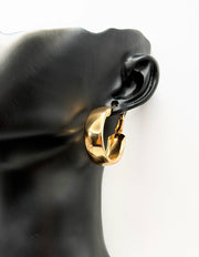 Gold hoop earring on a black mannequin ear against a white background