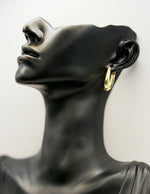 Gold hoop earring on a black mannequin bust against a white background
