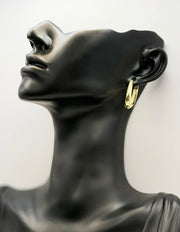 Gold hoop earring on a black mannequin bust against a white background