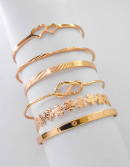 Gold engraved bracelets stacked with heart and floral details
