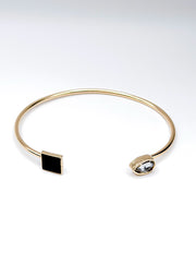 Gold bracelet with black and clear gemstones on a white background