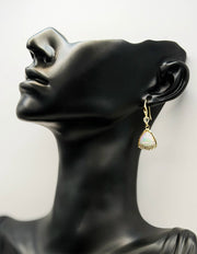 Gold earring on a black mannequin head with a white background
