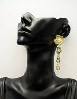 Gold earrings with pearls on a black mannequin head against a white background