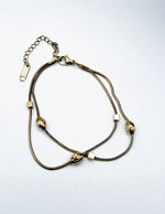 Close-up of non-tarnish gold bracelet with cubic and oval beads for stacking.
