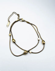 Close-up of non-tarnish gold bracelet with cubic and oval beads for stacking.
