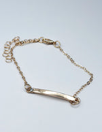 Gold bracelet with a bar clasp on a light gray background