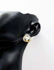 Gold earring with a pearl on a black mannequin ear against a white background