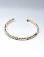 Gold bracelet on a light gray background