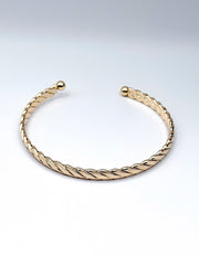 Gold bracelet on a light gray background